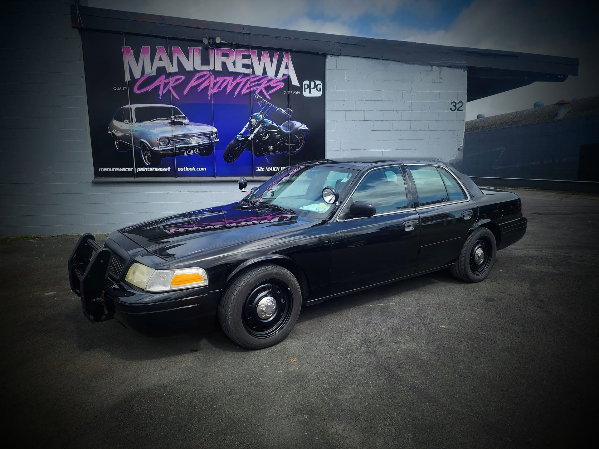 Freshly finished black sedan outside the workshop